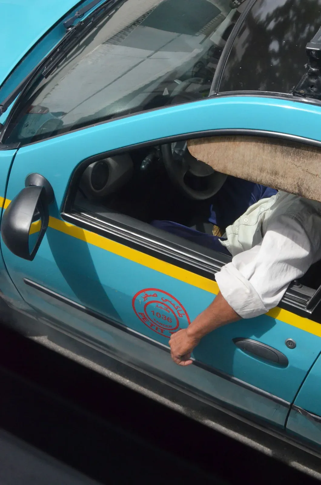 A blue Tangier petit taxi with a yellow stripe, photographed from above